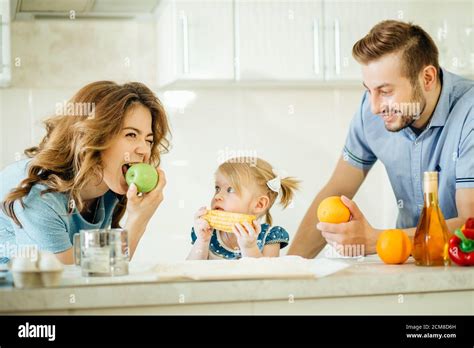girl and her parents are eating vegetables and smiling while cooking in ...
