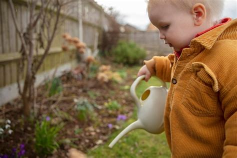 Premium Photo | A young child helping out in the garden watering plants ...