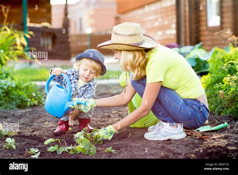 Child boy helps to mother working in the garden Stock Photo - Alamy