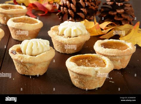 Assorted mini pumpkin tarts on a holiday table with pine cones and ...