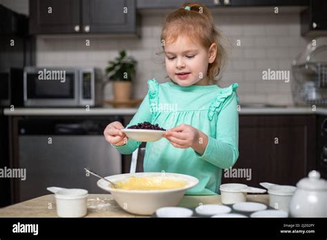 Little cute girl mixing ingredients for homemade blueberry muffins ...