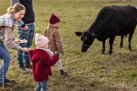 Girls with parents feeding animals in farm Stock Photo | Adobe Stock