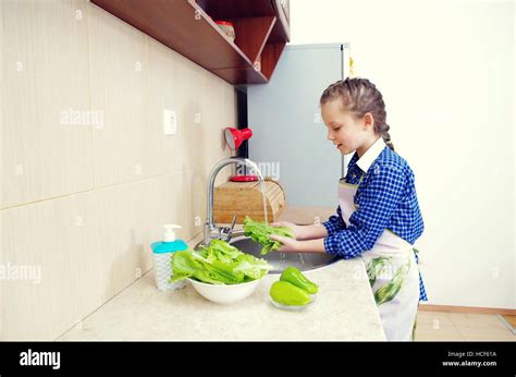 Little girl is washing vegetables for salad closeup Stock Photo - Alamy