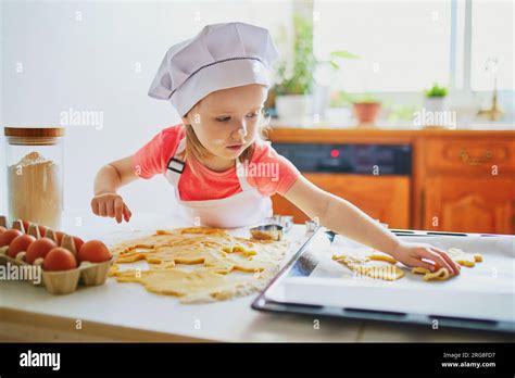 Adorable preschooler girl making cookies. Child helping to cook food in ...