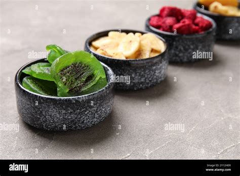 Bowls of different dehydrated fruits and berries on grey background ...