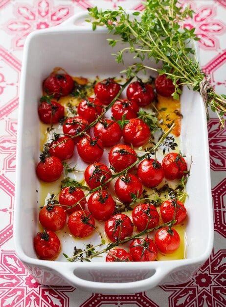 Premium Photo | Roasted cherry tomatoes with herbs in baking dish close up