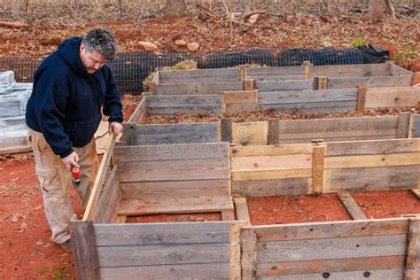 The Men are Constructing Raised Garden Bed Frame from Wood. Stock Photo ...