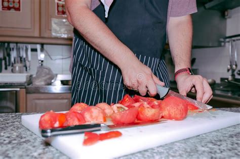 Chef in Apron Cutting Peeled Tomato on a Board in the Kitchen Stock ...