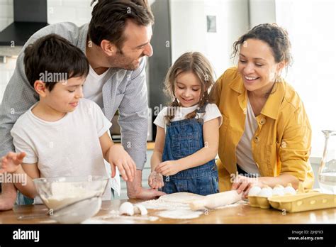 Happy family of four cooking in the kitchen together, parents and two ...