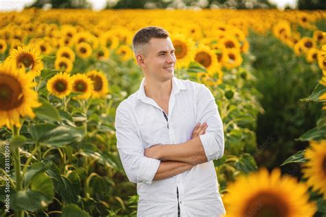 Happy smiling farmer standing proud in front of his sunflowers field ...
