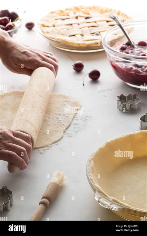 Hands rolling out dough in preparation of making a fresh cherry pie ...