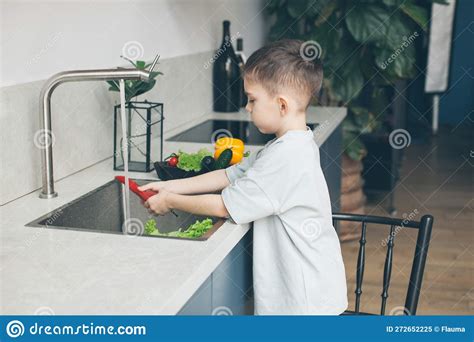 Six-year-old Boy Washing Vegetables in the Kitchen Sink. Side View ...
